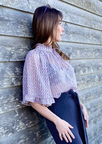 GDS Rina Blouse - a colourful tonal print in lilac, with pretty ruffled details on the wide bell sleeves and around the neck create a very feminine look.  Buttoned down the front with a tie at the neck this blouse is a real statement piece and looks stunning worn with just about anything, perfect with jeans when you want to look classy but keep it casual, or with tailored trousers or a skirt for a more formal look. 
