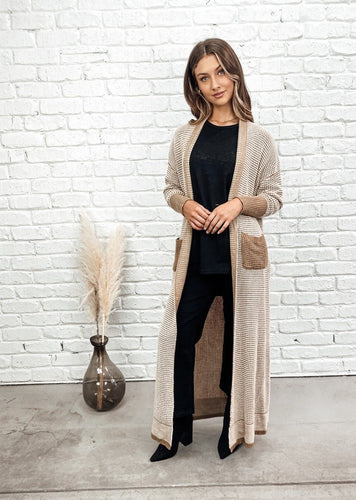 The Catacomb Long Cardigan by Bagira is a gorgeous full length length knitted cardigan that will work hard for you this winter season.  In a rich camel and white cotton blend knit, this cardigan is super soft, comfortable and warm.  The ankle length is flattering and elegant and can be worn with just about anything.  Featuring camel coloured pockets and cuffs, with reverse knit lapel detail and hemline, this sassy cardigan is urban elegance.  Wear to the office, or to watch the kids soccer game, 