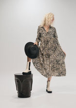 Load image into Gallery viewer, The Audrey dress is a lesson in edgy femininity with soft lines in a bold print.  Maxi length with full length sleeves and ruffle sleeve detail, with a collar and button down to the empire waist line.  Crafted from soft 100% Rayon, in a gorgeous zebra style print in black against cream, it really will be a long term favourite.
