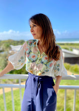 Load image into Gallery viewer, An allover floral print adds statement appeal to the GDS Carina Blouse.  Soft pastel colours and high-quality linen add to the affluent look of this stunning blouse.  Beautifully made, with puffed 3/4 length sleeves, and fabric buttons all down the front, to a high collar, this blouse looks stunning paired with jeans, or with tailored trousers 
