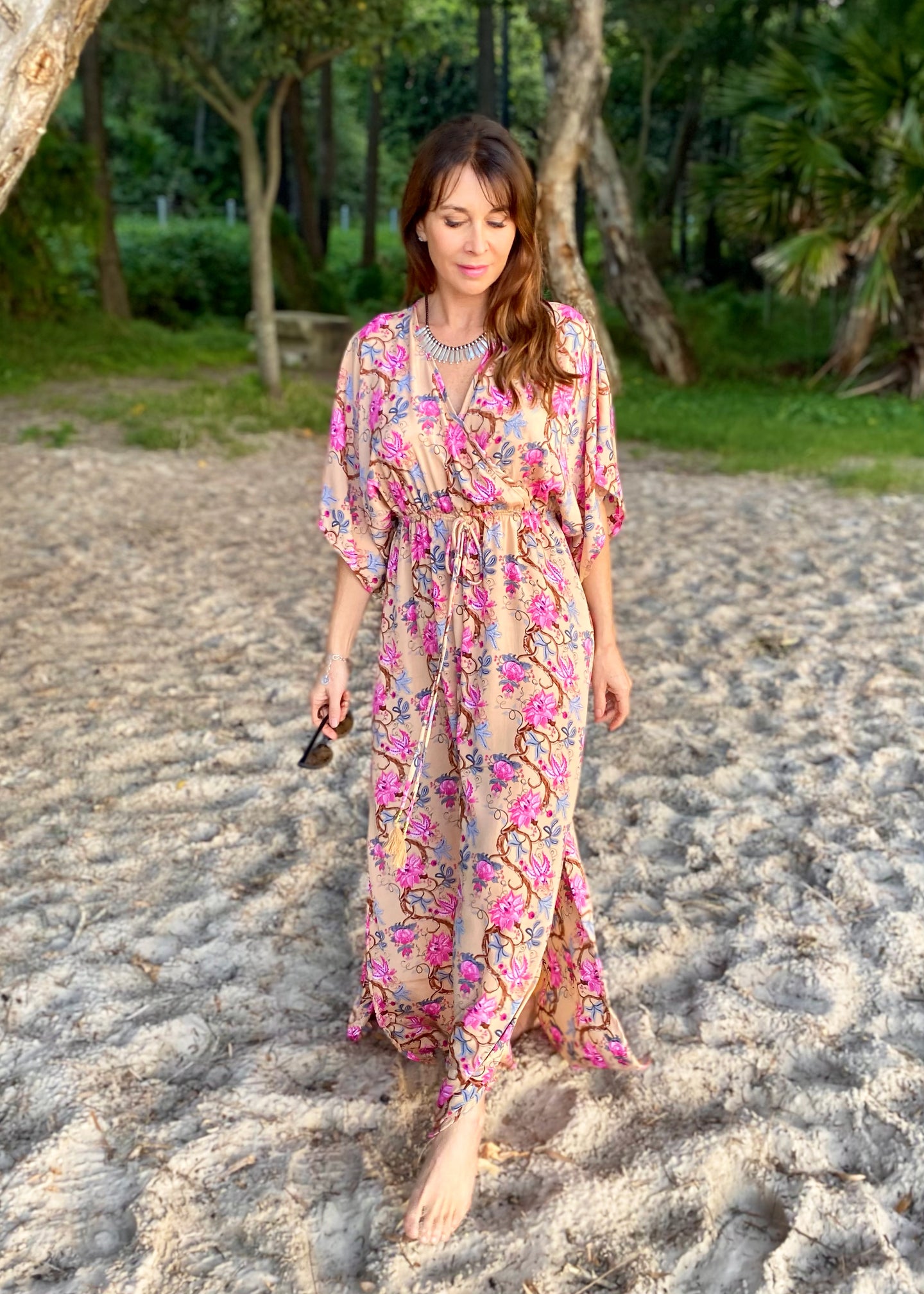 The Beatrice Dress -  the long loose flowing skirt lightly skims the body flattering the figure.  The silk blend fabric is lightweight and cool. The skirt is split at the sides to the knee and the V neckline crosses the bust with a drawstring tie under the bust, creating a flattering silhouette.  Finished with wide short bell sleeves, you will feel utterly feminine in the pretty floral print. 