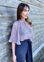 Load image into Gallery viewer, GDS Rina Blouse - a colourful tonal print in lilac, with pretty ruffled details on the wide bell sleeves and around the neck create a very feminine look.  Buttoned down the front with a tie at the neck this blouse is a real statement piece and looks stunning worn with just about anything, perfect with jeans when you want to look classy but keep it casual, or with tailored trousers or a skirt for a more formal look. 
