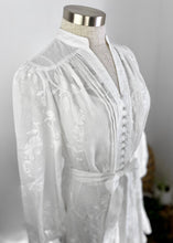Load image into Gallery viewer, The luxurious Abigail Dress by GDS, crafted of a rich linen weave, showcasts  romantic embroidery prints that add to the vintage look in this exceptionally feminine dress.  The lightweight 100% linen falls beautifully with soft, graceful movement. The embroidery is simple yet exquisite and adds a gorgeous feminine detail to the sheer linen.  Featuring delicate pleats down the front,  fabric buttons, a mandarin collar and finished with a pretty frill at the hem, just above the knee. 
