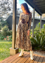 Load image into Gallery viewer, The Audrey dress is a lesson in edgy femininity with soft lines in a bold print.  Maxi length with full length sleeves and ruffle sleeve detail, with a collar and button down to the empire waist line.  Crafted from soft 100% Rayon, in a gorgeous zebra style print in black against cream, it really will be a long term favourite.
