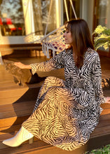 Load image into Gallery viewer, The Audrey dress is a lesson in edgy femininity with soft lines in a bold print.  Maxi length with full length sleeves and ruffle sleeve detail, with a collar and button down to the empire waist line.  Crafted from soft 100% Rayon, in a gorgeous zebra style print in black against cream, it really will be a long term favourite.
