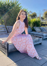 Load image into Gallery viewer, The stunning Amanda Floral Maxi in a gorgeous white floral print against a soft Blush pink background.  The long loose flowing skirt is tiered and belted at the waist. The halter neck is button at the back creating a shape that is very flattering.  The soft Poly Cotton fabric is lightweight and cool, perfect for a relaxed lunch with friends or an evening stroll along the beach.

