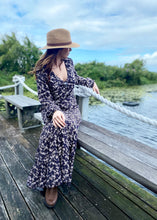 Load image into Gallery viewer, the limited edition Arcadia Elle Maxi dress is custom designed with bespoke prints by Fox&amp;Fallow. With a full skirt and a plunging frill neckline in a beautiful pale floral print against black.  It features a super flattering design with a v-neck tie front, gathered elasticized waist
