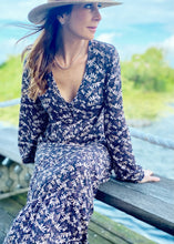 Load and play video in Gallery viewer, the limited edition Arcadia Elle Maxi dress is custom designed with bespoke prints by Fox&amp;Fallow. With a full skirt and a plunging frill neckline in a beautiful pale floral print against black.  It features a super flattering design with a v-neck tie front, gathered elasticized waist
