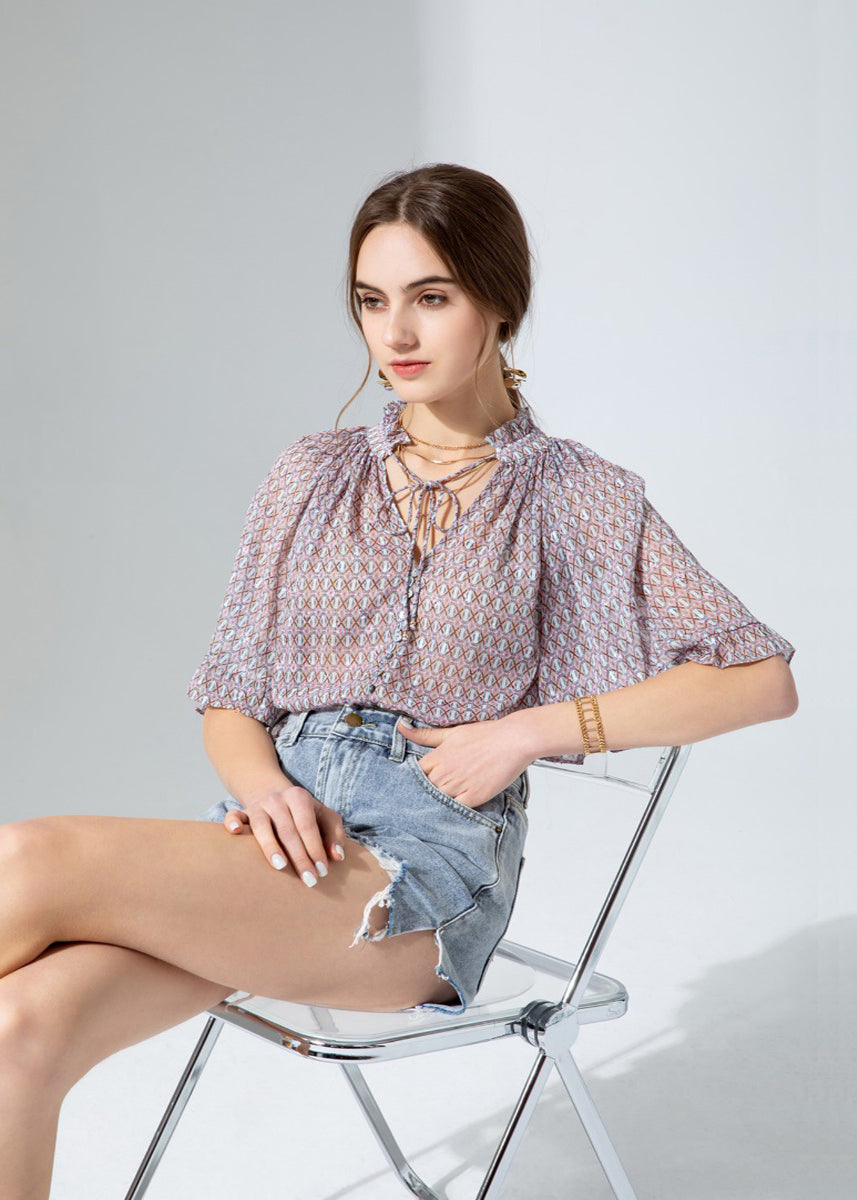 GDS Rina Blouse - a colourful tonal print in lilac, with pretty ruffled details on the wide bell sleeves and around the neck create a very feminine look.  Buttoned down the front with a tie at the neck this blouse is a real statement piece and looks stunning worn with just about anything, perfect with jeans when you want to look classy but keep it casual, or with tailored trousers or a skirt for a more formal look. 