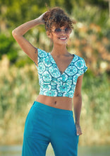 Load image into Gallery viewer, A colourful bohemian style crop top, with a cross over at the front and long straps that tie around the waist. A deep V neck and V back create a flattering feminine shape.  There is also a strap across the shoulders at the back to keep it secure.  The lovely Moroccan style print in aqua blue against white is both feminine and fresh and the viscose fabric is crisp and cool.   The deep V neckline and capped sleeves give it a elegant silhouette that pairs well with shorts, jeans or a skirt.
